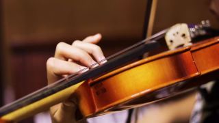 一个年轻的小提琴手模糊的左手按下小提琴颈上的弦，水平视频素材模板下载