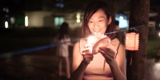 亚洲华人妇女在纸灯笼里点燃蜡烛，庆祝中秋节。