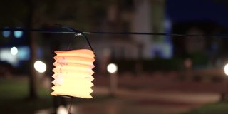 亚洲华人妇女在纸灯笼里点燃蜡烛，庆祝中秋节。