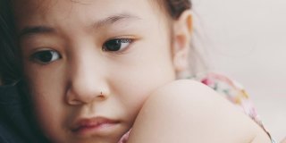 脸近4K可爱的5岁亚洲女孩在妈妈抱着哭的悲伤显示美丽的脸表达情感。是父母用爱呵护孩子。