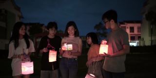 亚洲华人妈妈带着孩子和侄子拿着纸灯笼，庆祝中秋节。