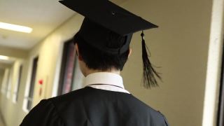 亚洲学生戴着学士帽，穿着学位服走在走廊上视频素材模板下载