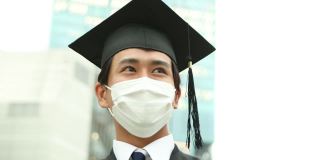 一幅亚洲学生的肖像，戴着学士帽，穿着学位服庆祝毕业