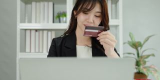 一位亚洲女商人正在用她的信用卡和笔记本电脑进行网上银行业务。技术和商业的概念