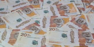 一堆钞票以扇形落在装满哥伦比亚钞票的平面上