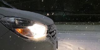 汽车的前灯照亮了雪景。缓慢的运动。