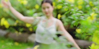 年轻的亚洲女人在花园里练习瑜伽。女性的幸福。模糊的背景。健康的生活方式和放松的观念。年轻的亚洲女孩在公园里做瑜伽。