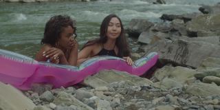 开朗可爱的多种族女性放松在充气床垫在山区河流