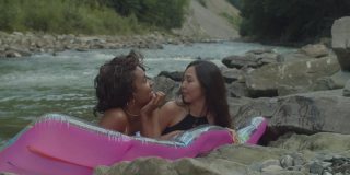 漂亮的多元文化女性朋友泳装享受在空气床垫在山河休闲