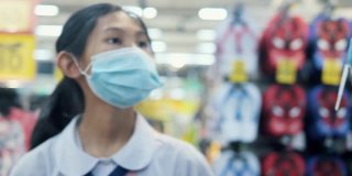亚洲女学生戴口罩，在超市的零售商店选购商品，新的正常生活理念。