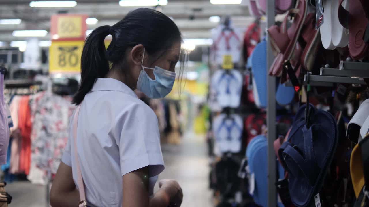 亚洲女学生戴口罩，在超市的零售商店选购商品，新的正常生活理念。