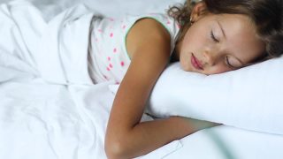 小女孩睡在一张又大又舒适的床上，白色的床单视频素材模板下载