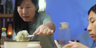 亚洲家庭的母亲和孩子晚上在家里一起吃涮锅或寿喜烧，生活理念。