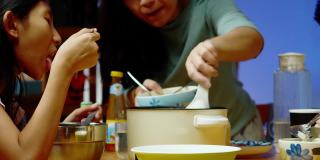 亚洲家庭的母亲和孩子晚上在家里一起吃涮锅或寿喜烧，生活理念。