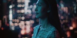 深夜霓虹灯下美丽的亚洲女性肖像站在城市街道。真实的成年自信女人在镜头前摆姿势，在市中心商业街的夜晚微笑。