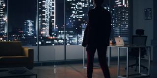 夜间办公室:强势的女商人穿着时髦的西装站在大城市的窗口向外看。管理电子商务环境、社会和公司治理的女性首席执行官