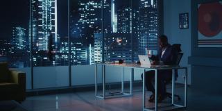 夜间办公室:成功的黑人商人穿着西装站着，看着窗外的大城市。非裔美国CEO对电子商务环境、社会、公司治理的思考