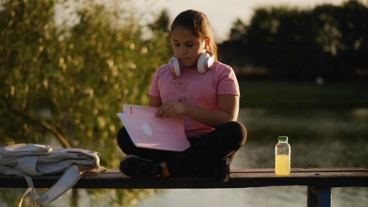 小女孩在湖边看书。一个年轻的少女正在翻看一本书