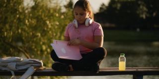 小女孩在湖边看书。一个年轻的少女正在翻看一本书