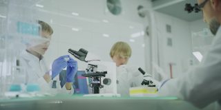好奇的男孩在实验室工作。使用显微镜和准备实验。跟着父亲学习，校准显微镜