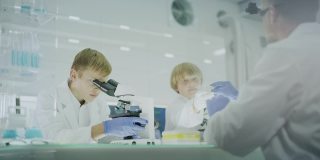 好奇的男孩在实验室工作。使用显微镜和准备实验。跟着父亲学习，校准显微镜