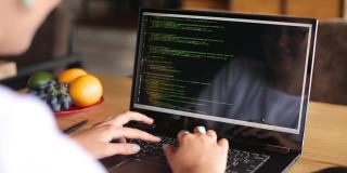 后视图越过肩膀的开发人员程序员女性与笔记本电脑。屏幕上的程序代码和脚本数据。年轻的自由职业者在咖啡馆做项目