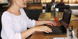 混合种族自由职业者转换笔记本电脑到平板电脑，而工作在咖啡馆。亚洲白人女商人与变压器笔记本。数码艺术家使用触摸屏二合一电脑