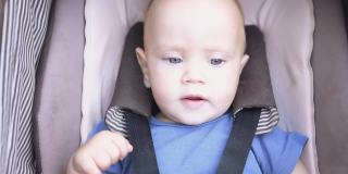快乐的蓝眼睛婴儿玩腿在棕色婴儿车在户外温暖