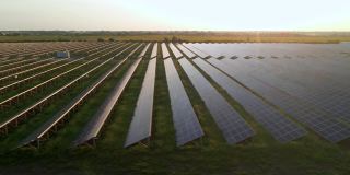 早春日落时，无人机在太阳能农场的大型太阳能电池板上观察。太阳能电池发电厂。录像视频4 k。