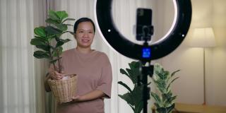 亚洲女性用智能手机在线直播，在家里卖人造植物