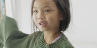亚洲女孩穿着绿色毛衣和姐姐在家里跳舞，生活理念。