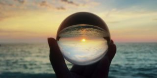 手持魔法水晶球越过美丽的自然景观，在日落，旅游的概念