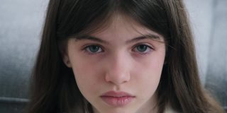 一个忧郁美丽的女孩的肖像，蓝色的眼睛和眼泪在她的脸颊上，少女哭泣
