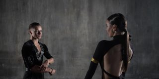 这对年轻的千禧一代舞蹈夫妇身穿黑色礼服，在摄影棚背景下以性感的姿势跳舞。