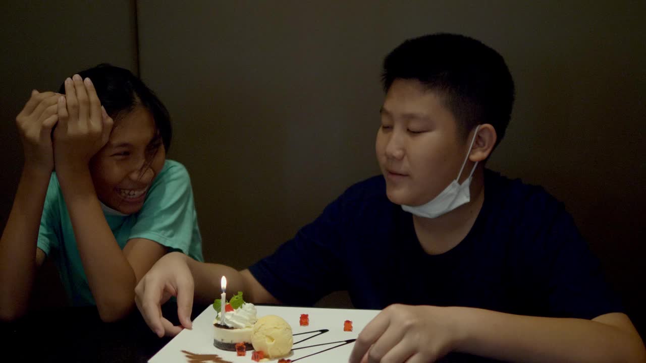 快乐的亚洲孩子们一起在餐厅为他们的兄弟庆祝生日，生活理念。