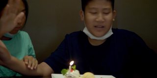 亚洲男孩和妹妹在餐厅吹生日蜡烛和冰淇淋蛋糕，生活理念。