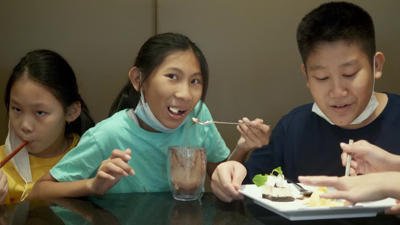 四个亚洲孩子一起在餐厅吃冰淇淋蛋糕庆祝生日，生活理念。