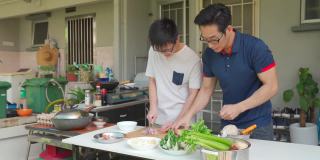 周末的时候，亚洲华人父亲和儿子在自家后院的厨房做饭，为家人准备晚餐