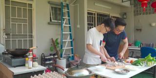 周末的时候，亚洲华人父亲和儿子在自家后院的厨房做饭，为家人准备晚餐