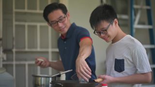 周末，一位亚洲华人父亲在自家后院的厨房教儿子做饭，准备晚餐视频素材模板下载