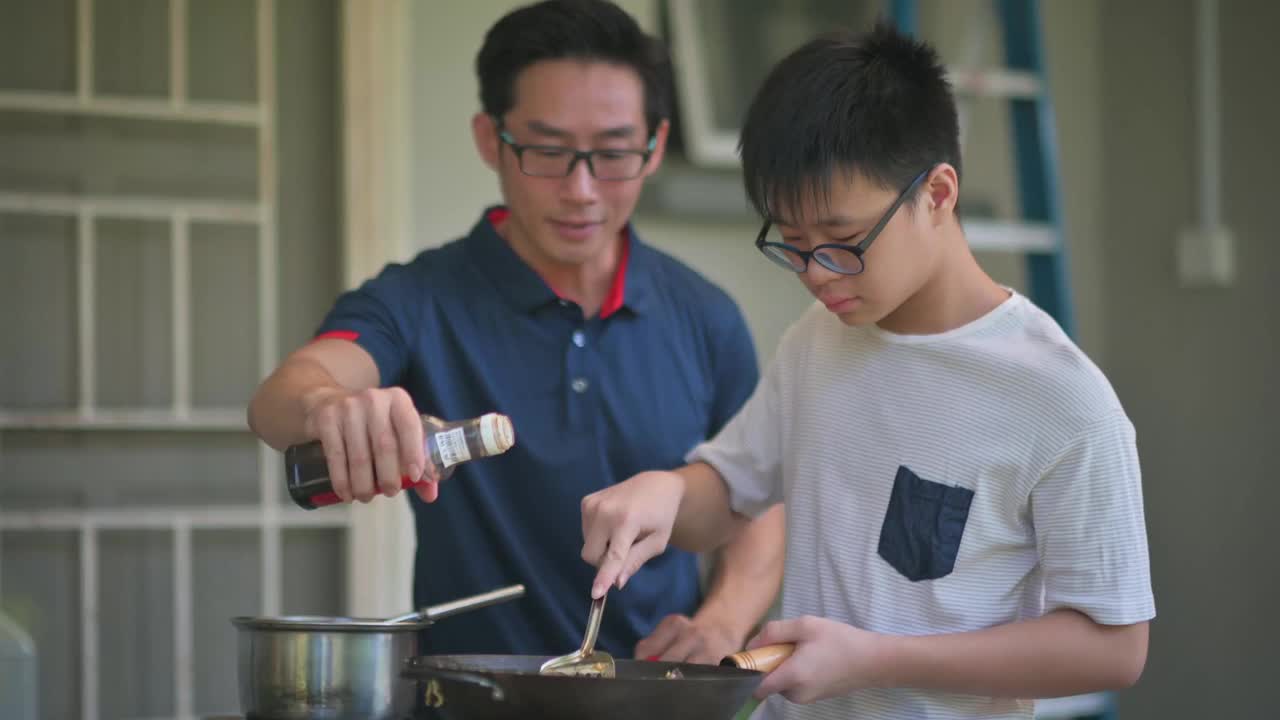 亚洲华人父亲和儿子周末在后院厨房做饭准备晚餐