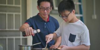 亚洲华人父亲和儿子周末在后院厨房做饭准备晚餐