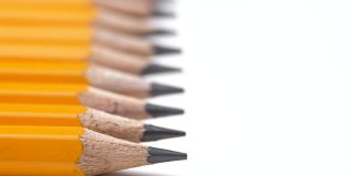 简单的灰色铅笔躺在一排，移动焦点在尖杆尖准备写作。木头铅笔作为创意艺术绘画。选择性聚焦锐利边缘。教育的概念。铅笔全景