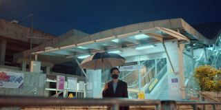 帅哥戴着防护口罩在城市的雨夜中行走。