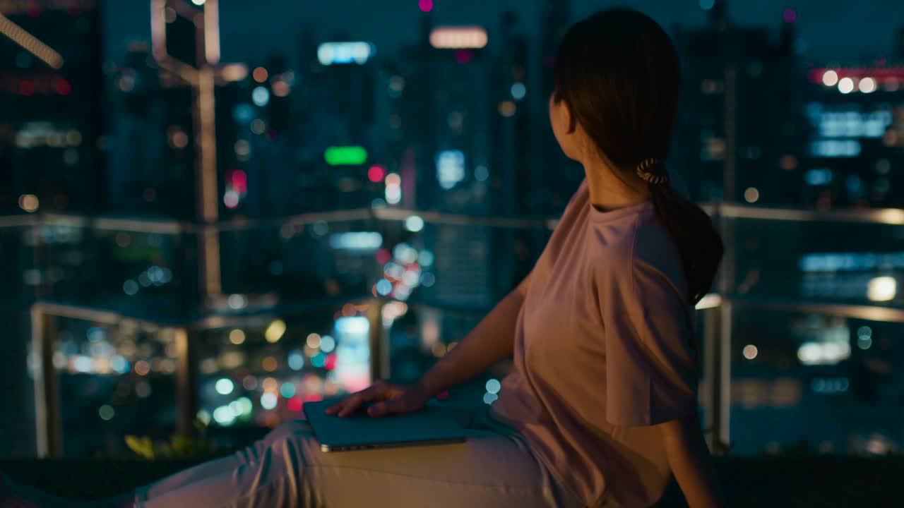 一个年轻女人的手在城市之夜用笔记本电脑