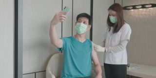 4K视频:患者和医生戴着防护口罩在医生办公室打疫苗自拍
