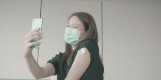 4K视频:一名妇女戴着防护口罩在医生办公室打疫苗时自拍