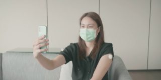 4K视频:一名妇女戴着防护口罩在医生办公室打疫苗时自拍