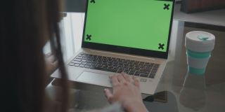 特写女人使用Chroma键屏幕笔记本电脑在家里的桌子上