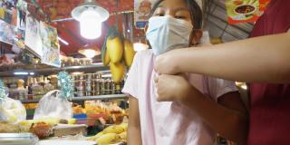在泰国著名海鲜店华欣夜市买芒果糯米饭的亚洲孩子们戴着口罩。